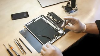 a person in gloves and gloves holding a piece of tablet repairing the broken tablet.