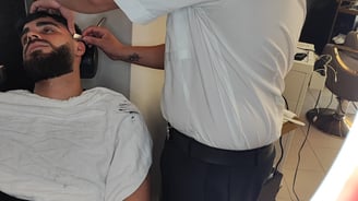 a man getting his hair cut by a barbershop