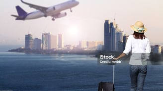 a woman standing on a beach with a suitcase and a suitcase