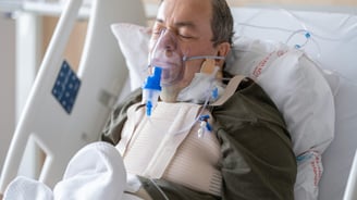 a man in a hospital bed with a mask on
