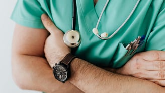 a man in a green scrubsuit with a stethoscope attached to his