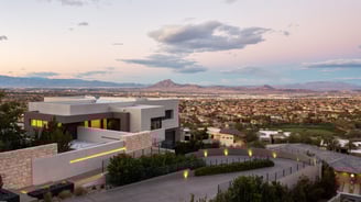 Contemporary hillside home overlooking cityscape and desert mountains.