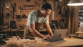 a man in a workwear suit and glasses working on a laptop