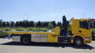 a yellow truck with a crane on it's back