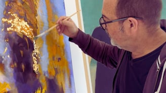 Martin Osner applying gold leaf to a mixed media artwork in his studio