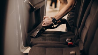 Nettoyage de la banquette arrière d'une voiture avec un aspirateur.