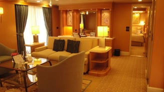 Vista da suíte luxuosa em navio de cruzeiro, com decoração refinada e amplo espaço interno.