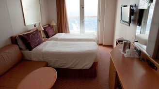 Cabine com duas camas de solteiro em navio de cruzeiro, em layout compacto e bem aproveitado.