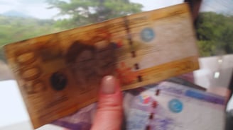 Autora segurando notas de peso filipino, com cenário local ao fundo.