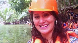 Autora sorrindo ao final do tour pelo Rio Subterrâneo, com vegetação tropical ao fundo.