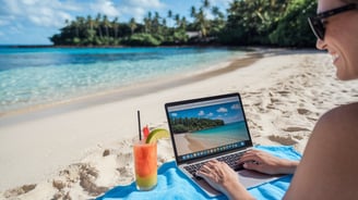 uma mulher sentada na praia com um laptop