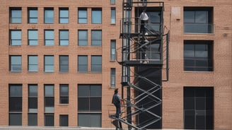 a man standing on a lift lifter in front of a building