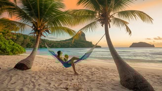 a woman sitting in a hammock on a beach