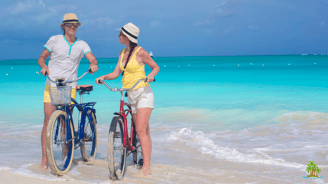 a man and woman standing in the ocean with their bikes