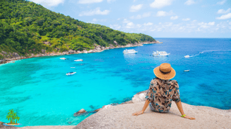 a woman sitting on a rock overlooking a sea in Thailand