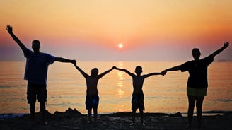 a family of four standing on a beach