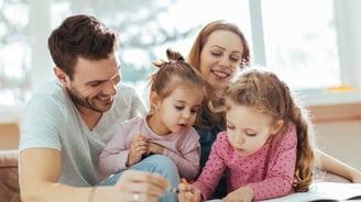 Mother and father reading a book with their two daughters