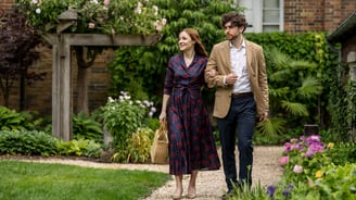 a man and woman walking down a path in a garden
