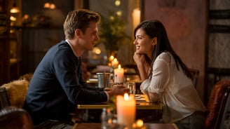a man and woman sitting at a table with candles