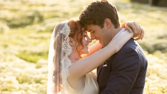 a bride and groom standing in a field
