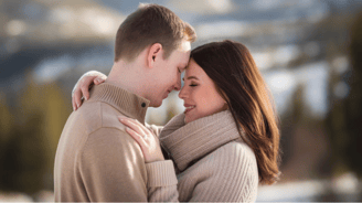 a couple standing in the snow with their arms around each other