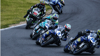 Gruppo di piloti in curva durante gara motociclistica, esempio di progetto gestito da Noline.