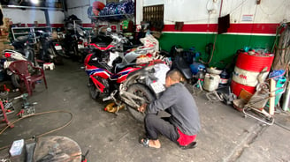 a man in a gray shirt is working on a motorcycle