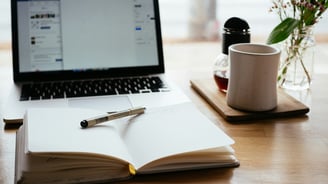 otwarty zeszyt z długopisem przy laptopie, widzimy że ktoś uczy się fizyki albo matematyki