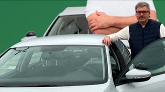 a man standing next to a car with a woman in a vest