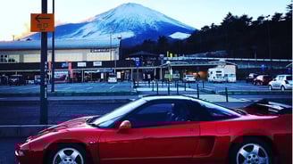 a red sports car parked in front of a mountain