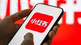a person holding a phone with a red and white sign