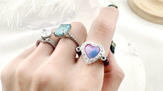 Gold-toned chain accessories featuring heart-shaped links and enamel flower charms in white and blac