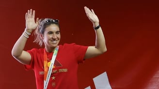 a woman in a red shirt and sunglasses is holding a medal