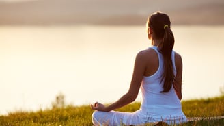 a woman sitting in a field meditating