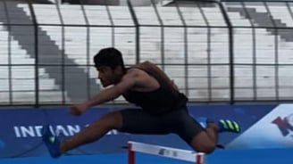 a man is jumping over a hurdle in a stadium