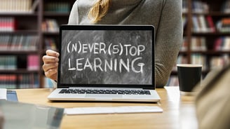 a woman showing a laptop computer screen saying never stop learning