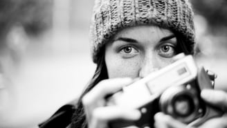 Student in fine art photography courses holding a vintage camera, black and white portrait.