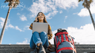 a woman sitting on stairs with a laptop and a backpack
