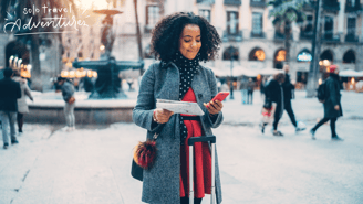 a woman in a coat and scarf standing in a city