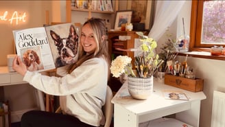 Alex Goddard in her studio with the magazine feature that she was featured in