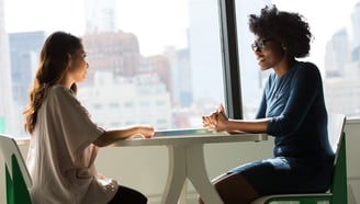 two women talking at a table supporting each other