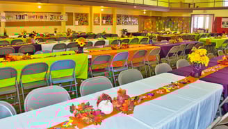 a large room with decorated tables and chairs with a birthday celebration banner