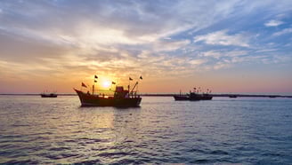a boat in the water with a sunset in the background