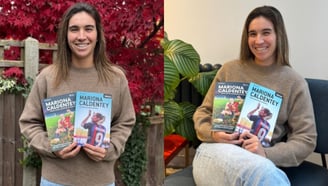 two women holding up their books and smiling