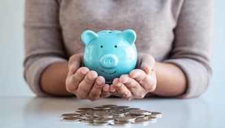woman holding a piggy bank with coins on the table for retirement