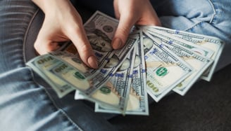 person holding a wad of 100 dollar bills in their hand