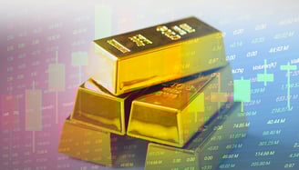gold bullion bars in a pile with candlesticks and chart data