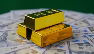 gold bars in pyramid on top of 100 dollar bills