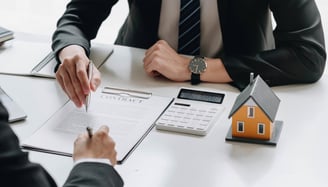 mortgage papers being signed with a calculator on the side for knowing rates