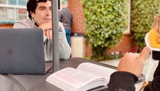 A Team Guide member sitting behind a table listening with his arm folded.